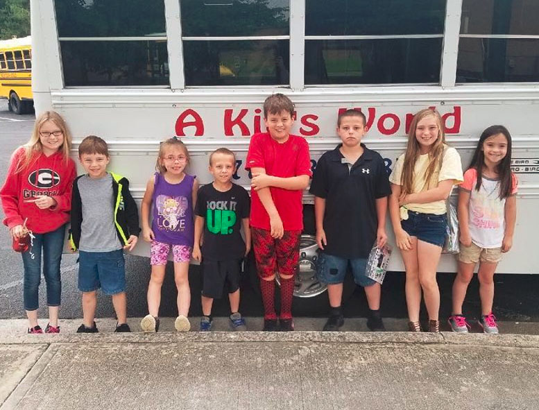 Group of diverse kids beside their school bus at a Christian Preschool & Daycare Serving Loganville, GA