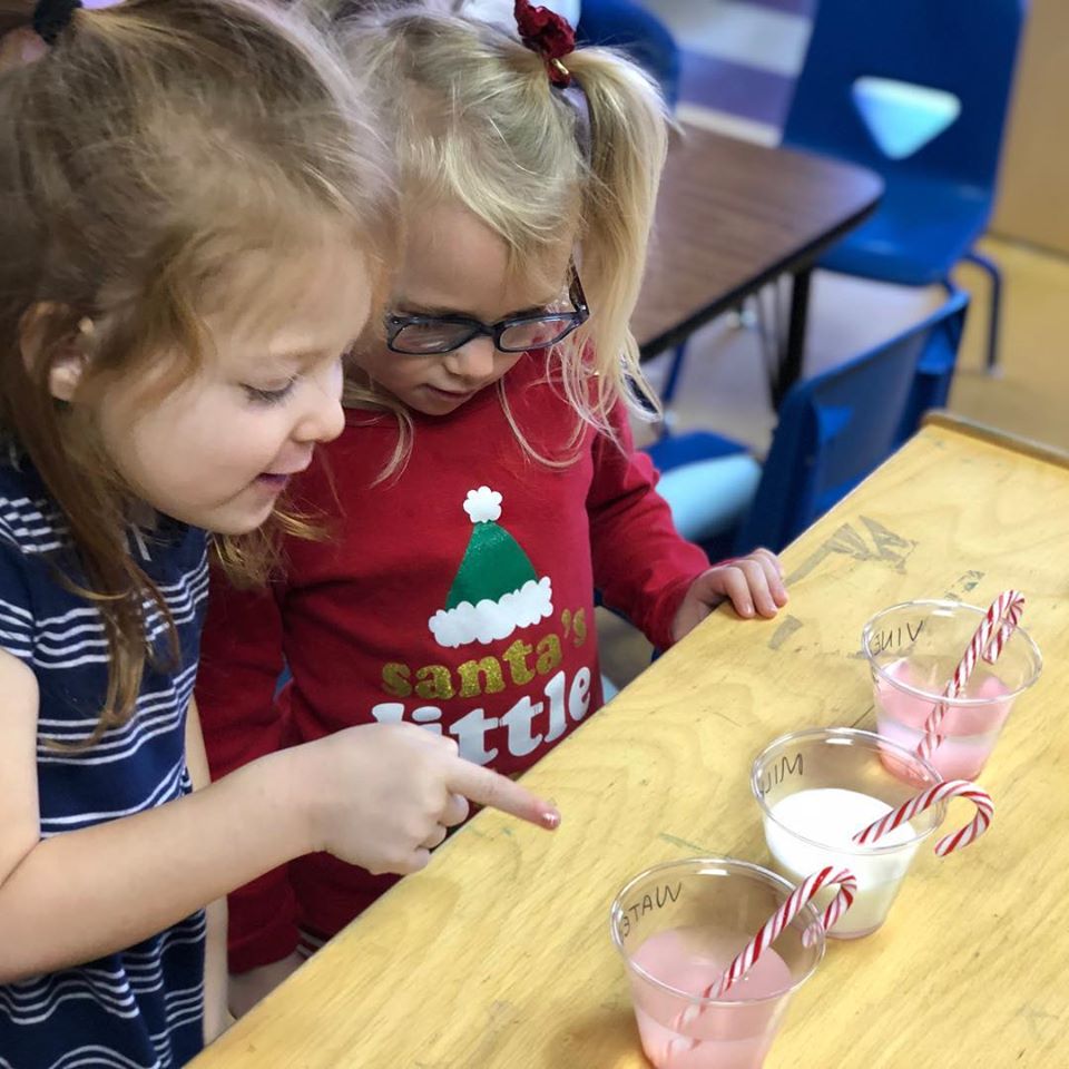 Two little girls choosing from a 3 cups of fruit shake with a candy cane on top at a Christian Preschool & Daycare Serving Loganville, GA