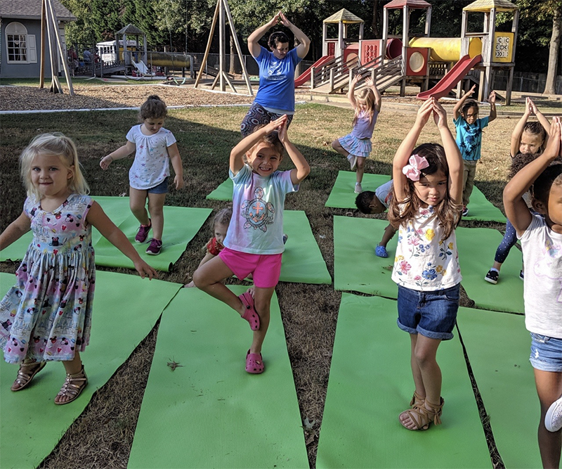 Group of kids doing yoga with their teacher on a playground at a Christian Preschool & Daycare Serving Loganville, GA